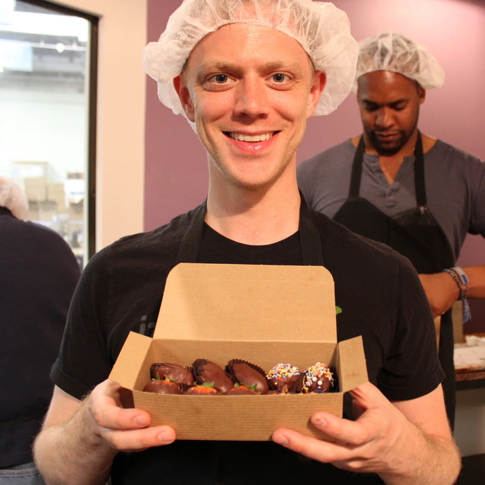 Guest holding a box of chocolate dipped fruit
