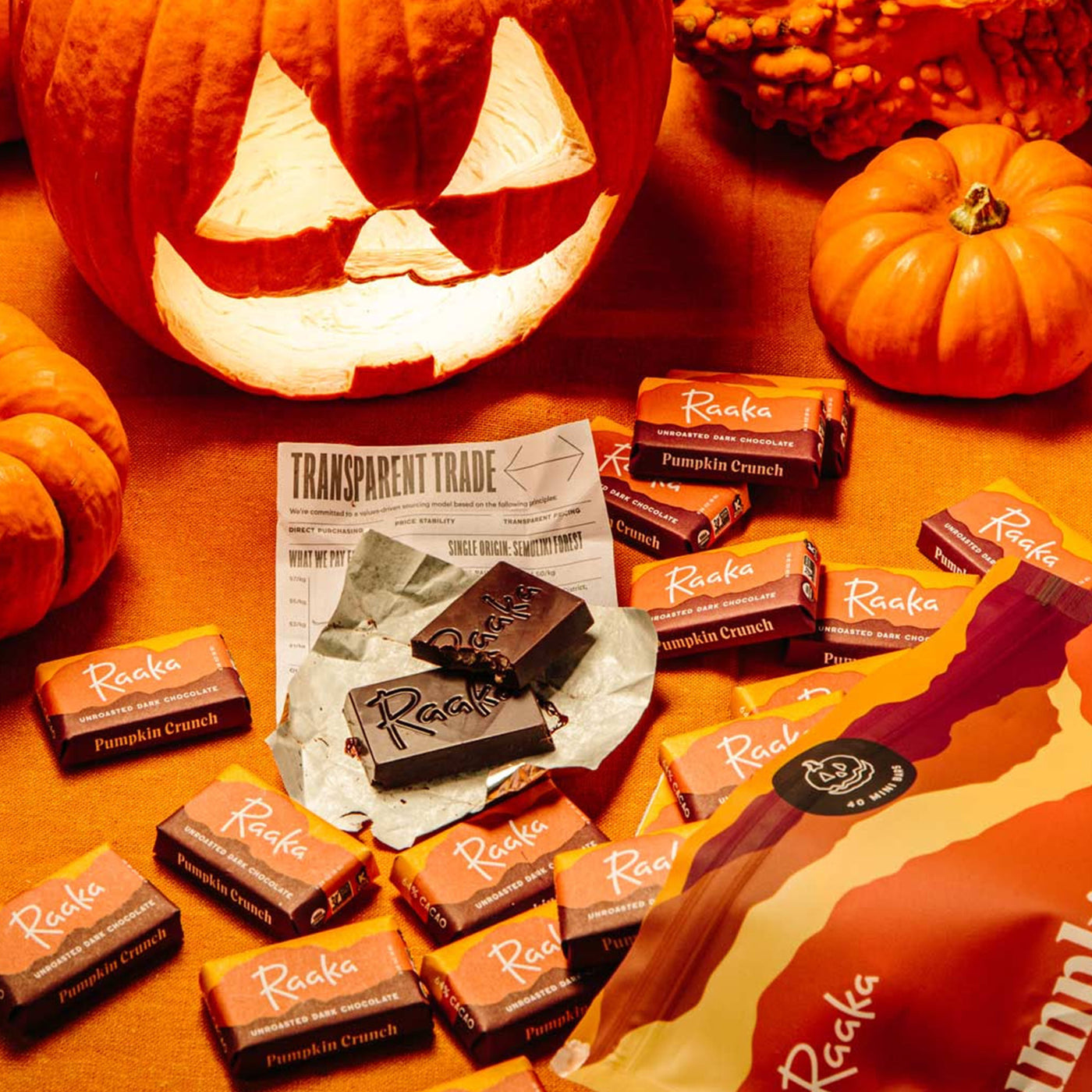 Pumpkin Crunch Mini Bars spilling out the bag on a table with a jack-o-lantern and mini pumpkins.
