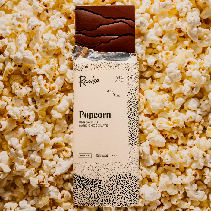 Raaka Popcorn dark chocolate bar packaging on buttery popcorn