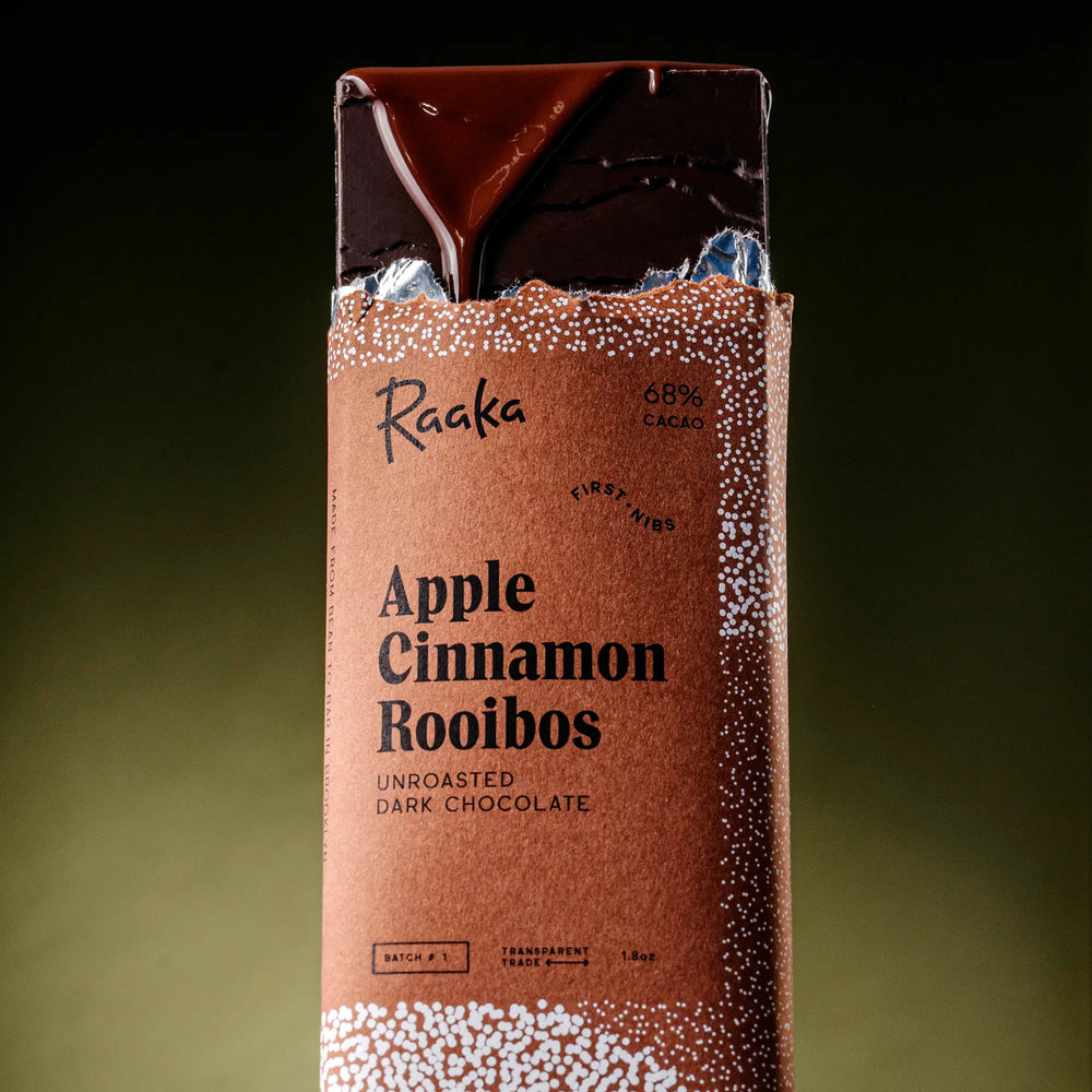 Raaka Apple Cinnamon Rooibos dark chocolate bar packaging on a gradient background
