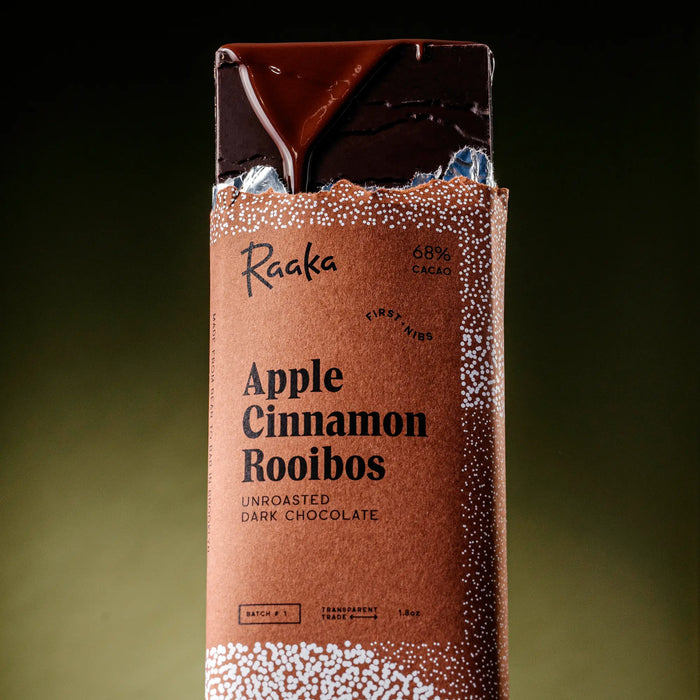 Raaka Apple Cinnamon Rooibos dark chocolate bar packaging on a gradient background