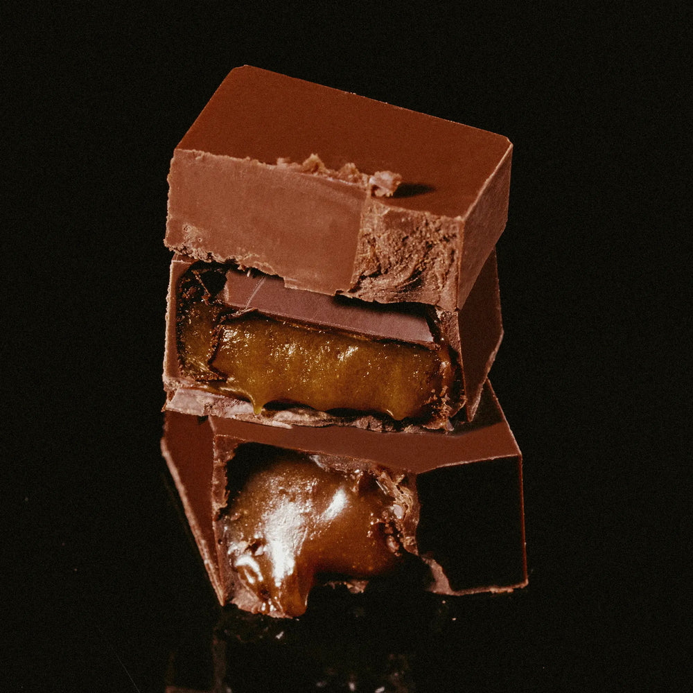 Stack of date-sweetened dark chocolate truffles with caramel filling on a black background