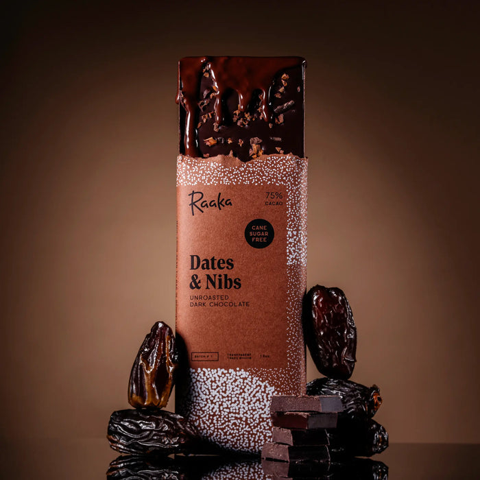 Date and Nibs bar with melted chocolate in wrapper, with dates and chunks of chocolate around.