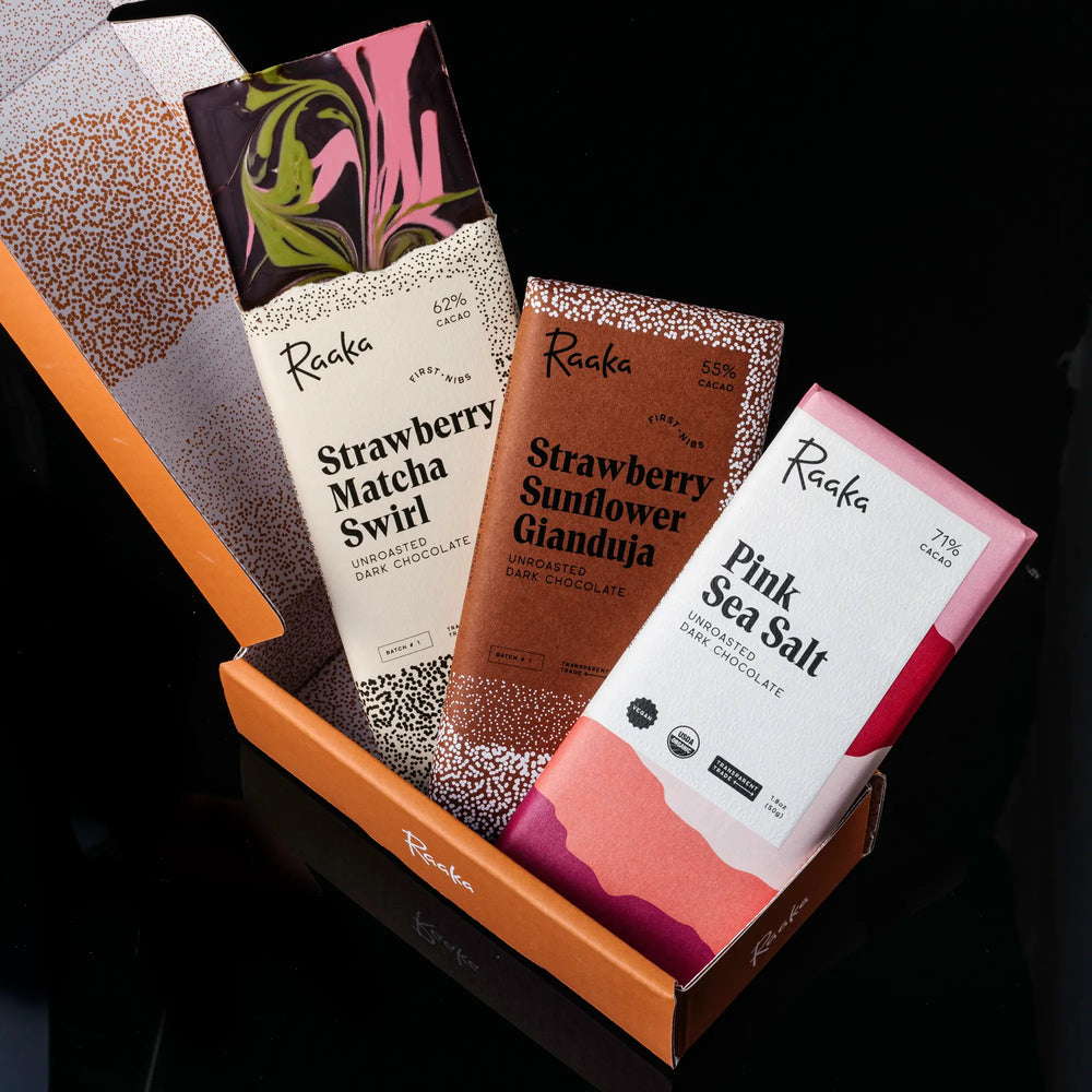 Assorted Raaka chocolate bars in an open box on a black background