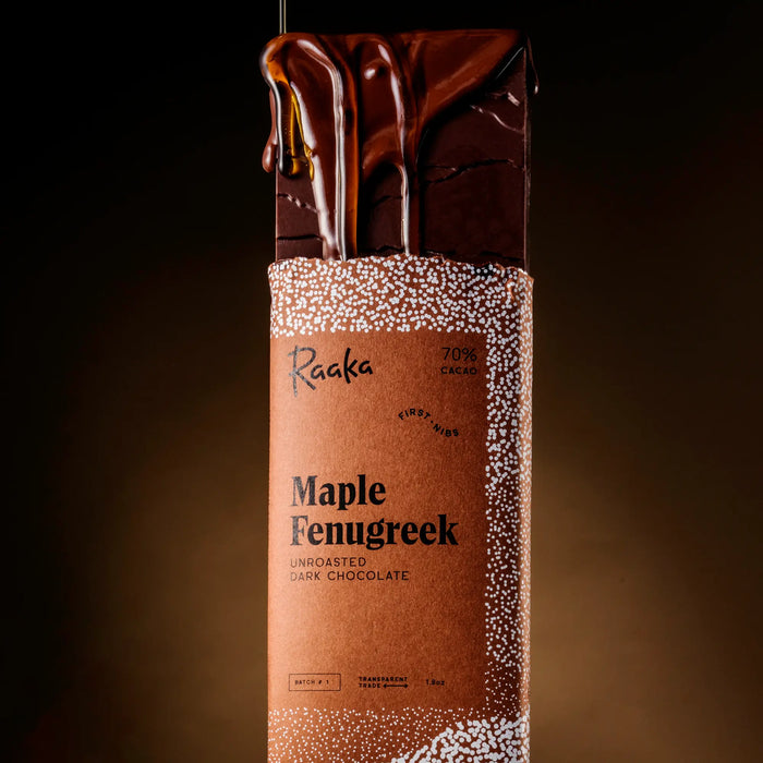 Maple Fenugreek dark chocolate bar with Raaka branding on a dark background. Maple syrup dripping on bar.