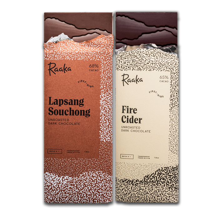 Two Raaka chocolate bars, in October's First Nibs batch: one 'Lapsang Souchong' and the other 'Fire Cider', on a white background.