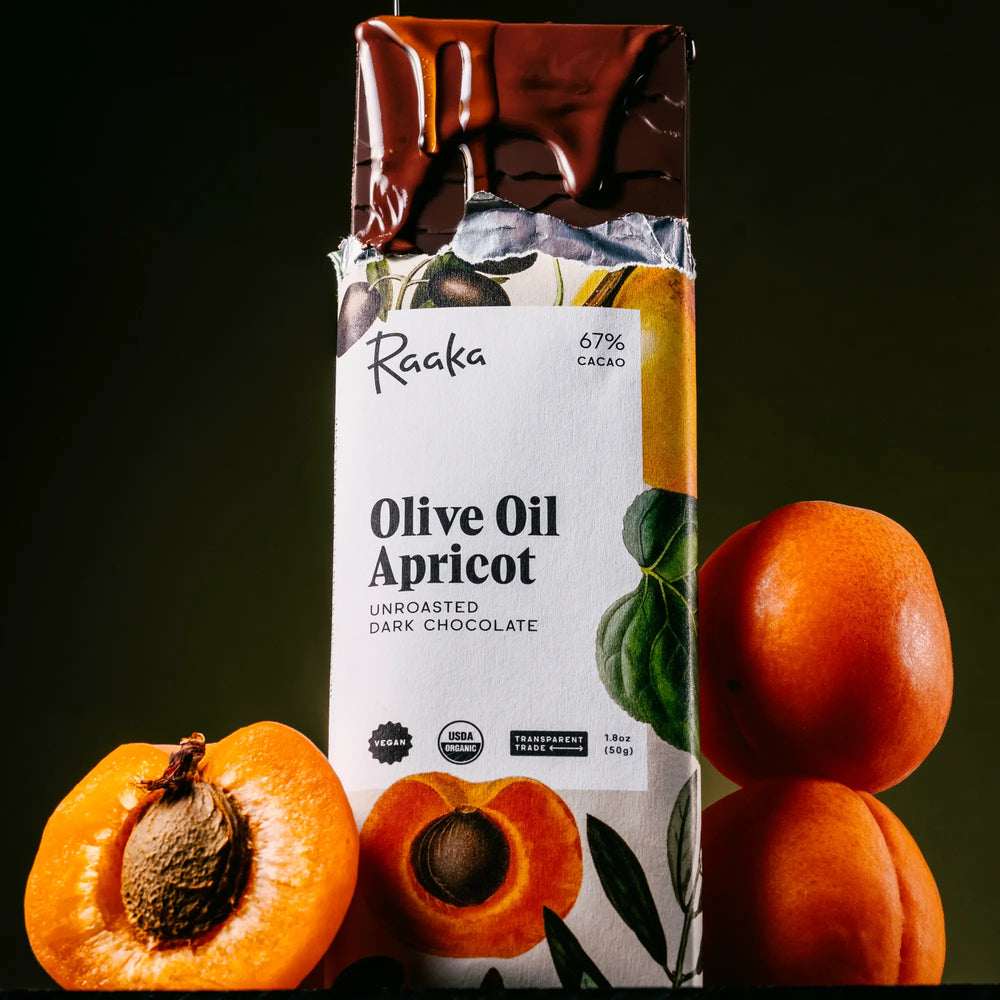 Raaka Olive Oil Apricot chocolate bar with apricots on a dark background