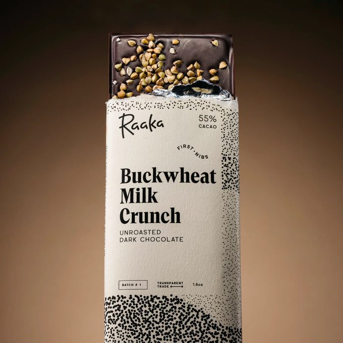 Raaka Buckwheat Milk Crunch chocolate bar packaging on a brown background