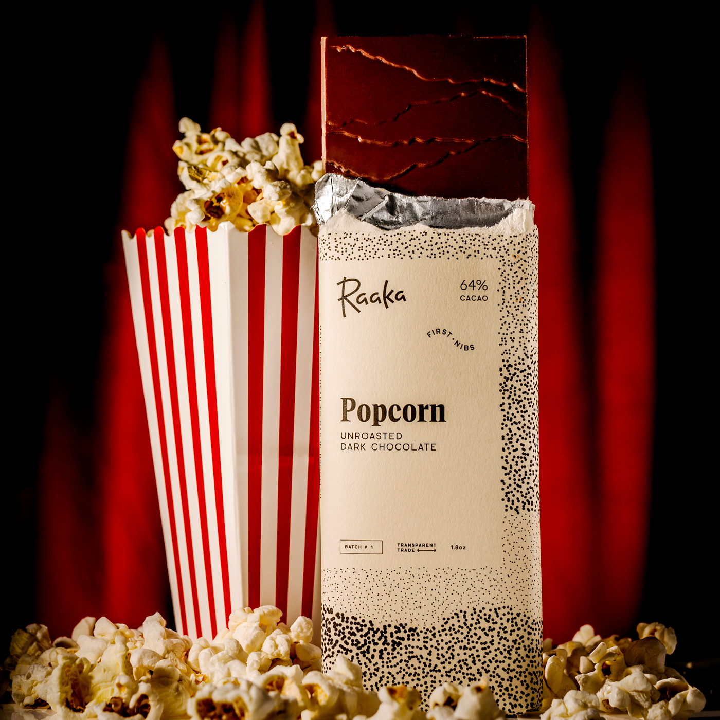 


Raaka Popcorn packaging with popcorn spilling out against a red curtain background