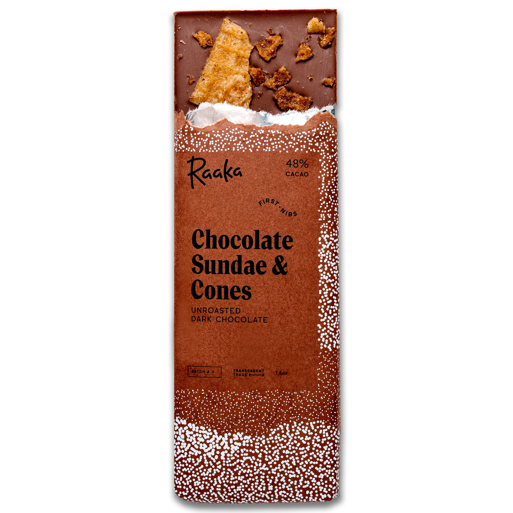 A packaged chocolate bar labeled 'Raaka Chocolate Sundae & Cones' on a plain white background. The wrapper is predominantly brown with white speckled edges and shows a partially unwrapped dark chocolate bar at the top with cookie pieces embedded in it.