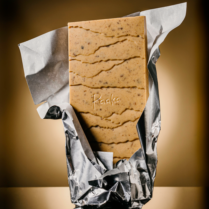 Sweet Potato Pie bar popping out wrapper. Bar is orange tinted and filled with bits of pumpkin spice cookies.