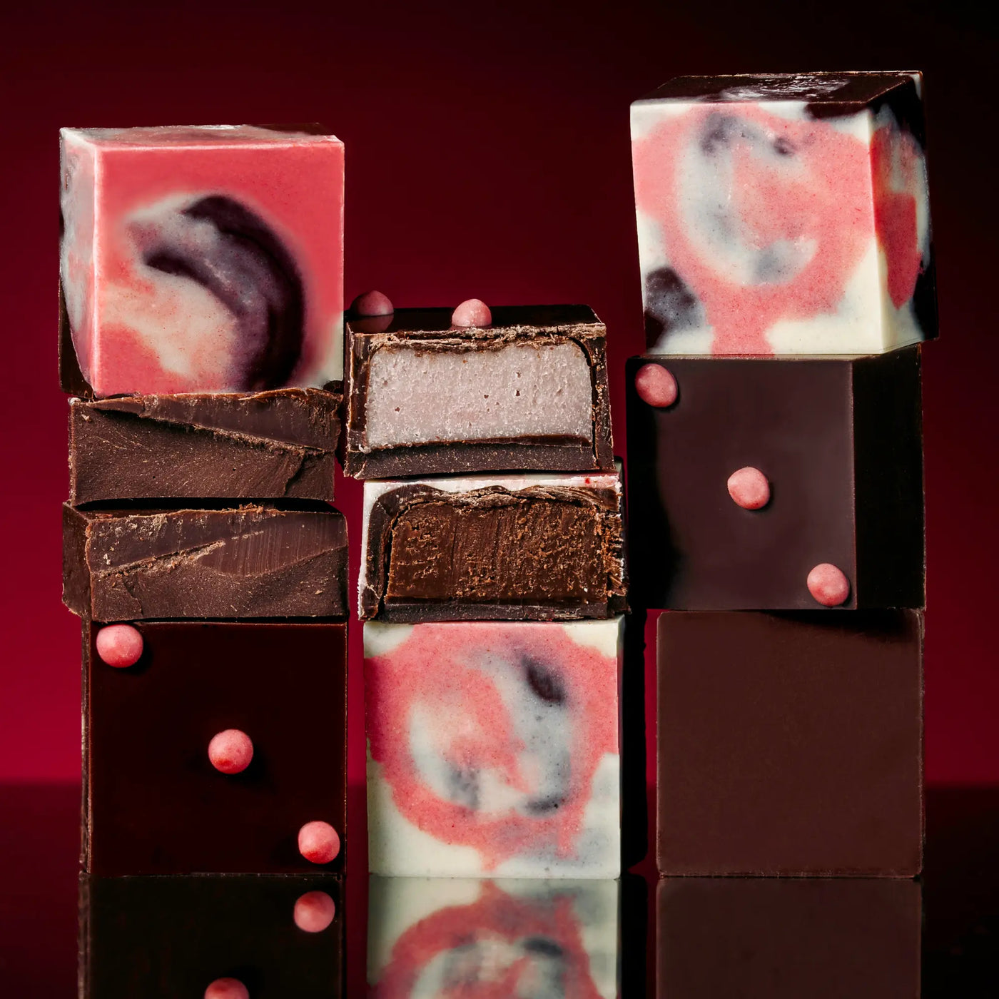 Stack of multicolored truffle chocolate pieces with a red background