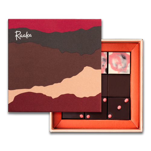Open box of chocolates with a decorative lid featuring the brand 'Raaka'.